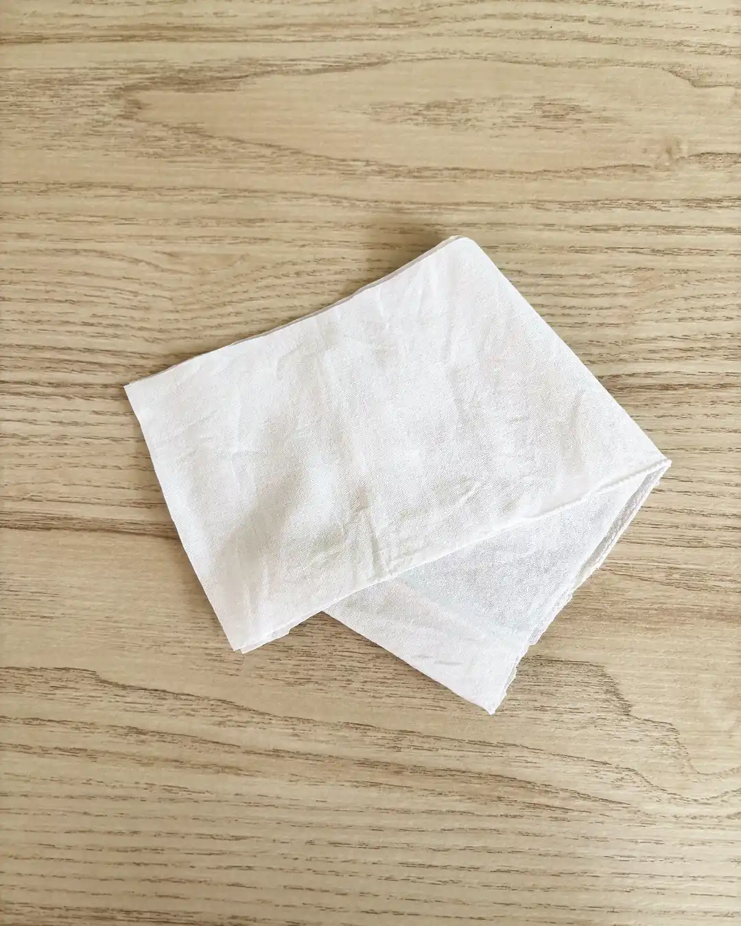 Pièce de tissu en coton popeline pliée sur une table en bois clair